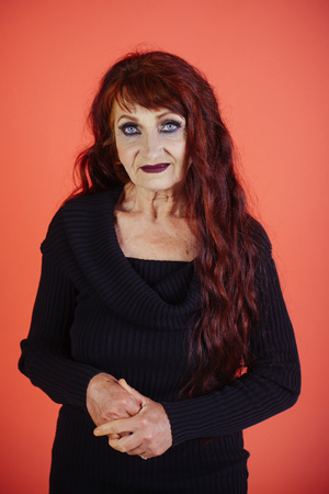 Woman with long dyed hair color, hairstyle. Senior model with wrinkled face, aging skin, makeup, look. Anti aging, rejuvenation, lifting. Skincare, skin therapy. Age, beauty, make up, fashion.の写真素材