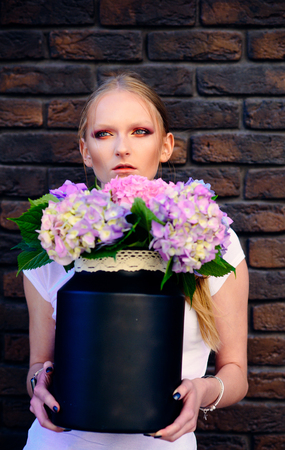 Floristry, floristic design, floral shop. Woman hold vase with hydrangea flowers on brick wall....