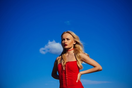 woman in summer on blue sky background. Beauty and fashion, look. Girl with sexy legs, loneliness. Freedom and expectation. Woman with blonde hair outdoor.の写真素材