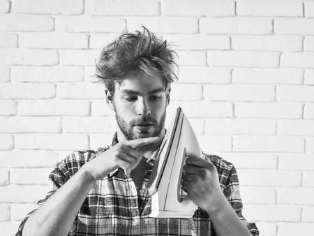Young Handsome Man In Stylish Plaid Shirt Touches White Iron