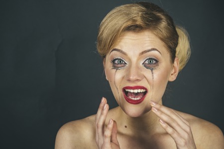 Drama and shock concept. Girl cry with mascara streams on face. Lady with blonde hair and elegant hairstyle cry. Woman with shocked face with makeup on grey background, copy space.の写真素材