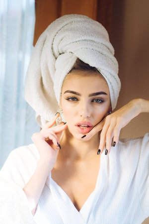 Girl with towel on head relaxing, after spa or morning shower. Lady with mysterious face and decollete. Woman in bathrobe after wellness and skin care procedures. Rest, wellness and and care concept.の写真素材