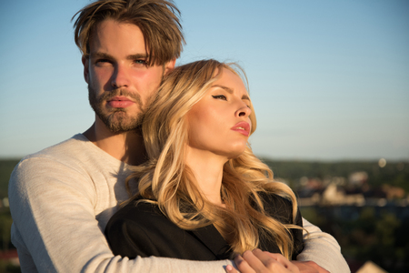 Family couple of man and sexy girl, trust. Muscular man and woman with long blond hair, love. Couple in love on blue sky background. Love and romance. Relations of happy family, future.の写真素材