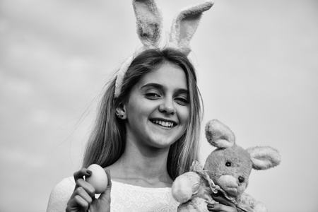 yellow painted easter egg as traditional spring holiday food and rabbit toy, happy girl in pink...