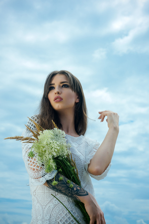 Beauty, fashion, look, makeup, visage. Sensual woman with flowers cloudy sky, beauty. Skincare, treatment, therapy, spa. Woman with floral bouquet, fashion. Womens day, 8 march, spring, summer.の写真素材