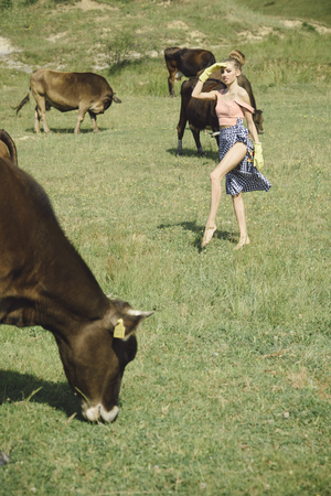 Cow, woman in countryside pasture, ecology. Dairy, milk production, industry. Village, farming, field grazing, beef meat. Veterinarian on farm feeding cow. Woman farmer, vet, dairymaid, agriculture.の写真素材