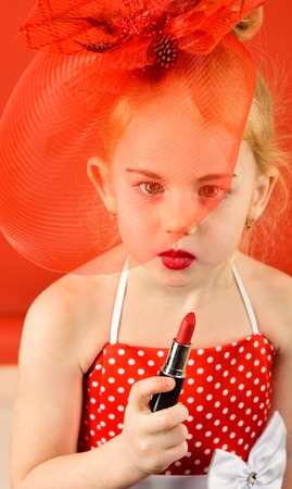 Makeup, retro look, hairdresser, pin up. Retro girl, fashion, cosmetics, beauty. Little girl hold lipstick and mirror.の写真素材