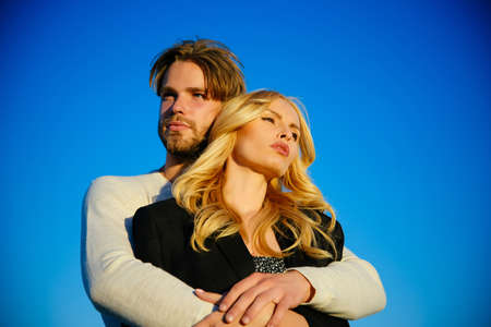 Relations of happy family, future. Love and romance. Muscular man and woman with long blond hair, love. Family couple of man and sexy girl, trust. Couple in love on blue sky background.の写真素材