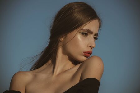 Beauty and fashion, cosmetics. Hairdresser and skincare, summer fashion. Fashion look of stylish woman in black, makeup. Elegant woman with long hair. girl with red lips on blue sky background.の写真素材