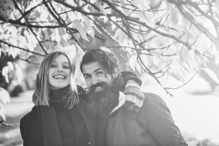 Young couple of pretty girl and bearded man hipster outdoors in autumn park with yellow leaves on natural background in colorful glovesの写真素材