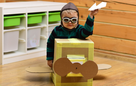 Dream, career, adventure, education. Air mail delivery, aircraft construction. Kid, pilot school, innovation. Little boy child play in cardboard plane, childhood. Pilot travel, airdrome, imagination.の写真素材
