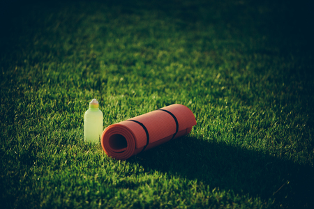 Mat and plastic bottle on green grass. Mat for fitness, yoga, sport, training, activity.の写真素材