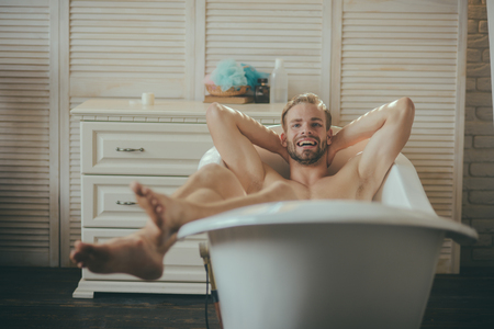 Smiling cute man having joyful morning in bathtub.の写真素材