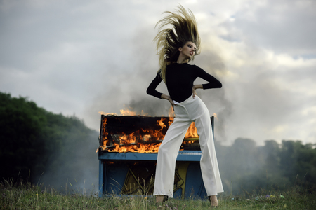 Woman in white pants at burning pianoの写真素材