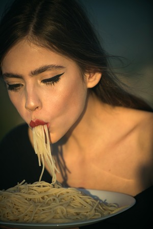 Italian macaroni or spaghetti for dinner, cook. Woman eating pasta as taster or restaurant critic. Chef woman with red lips eat pasta. Diet and healthy organic food, italy. Hunger, appetite, recipe.の写真素材