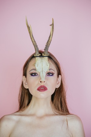 Beauty of woman with animal skull and antlers. Beauty look and cosmetics for skincare.の写真素材