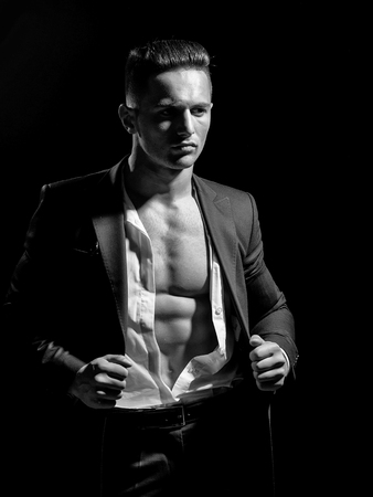 young handsome gentleman wearing fashion black suit in white open shirt with bare torsoの写真素材