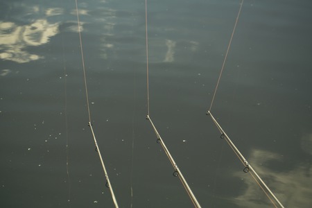 Tackles, cords for angling in river, lake, pond, freshwater. Rods and lines on blue water surface,...