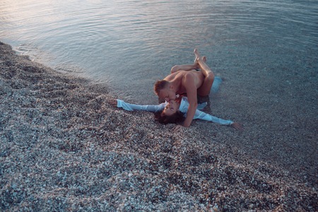 Sex in ocean concept. Couple full of desire have sex in sea water. Sensual lovers making love at seashore, sunset. Couple in love nude have sex, makes love in transparent ocean water.の写真素材