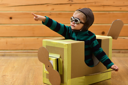 Kid, pilot school, innovation. Dream, career, adventure, education. Little boy child play in cardboard plane, childhood. Pilot travel, airdrome, imagination. Air mail delivery, aircraft construction.の写真素材