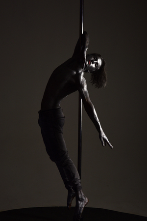 Man with nude torso dancing with poleの写真素材