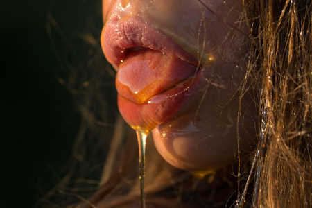 closeup of female sexy mouth with honeyの写真素材