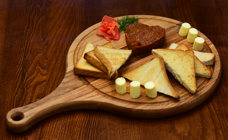 Tatar beefsteak served in shape of heart on round wooden board. Bread, toast and butter around beefsteak on board. Restaurant dish concept. Dish appetizing decorated with dill.の写真素材