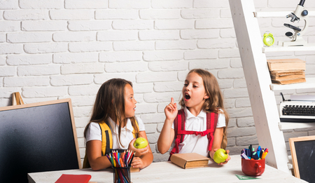 School time of girls. Little girls eat apple at lunch break. Happy school kids at lesson in...