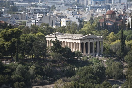 Ruins of ancient Greek temple surrounded by park or forest. Old building with columns with modern city, urban background. Confrontation of ages. Cultural and architectural heritage.の写真素材