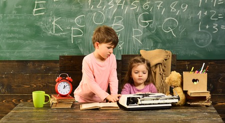 Attentive students writing something in their note pads while sitting at desks in the classroom....