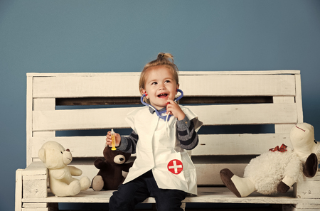 Happy baby with toy pets sit on wooden benchの写真素材