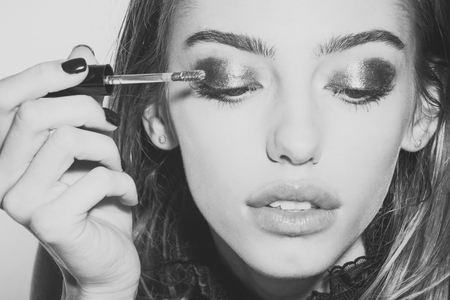 Girl put eyeshadow on eyes with brush, new technology.の写真素材