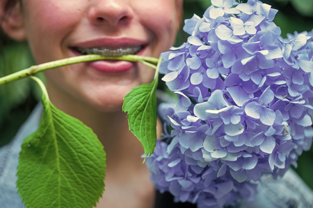 Blue hydrangea flower in female mouth
