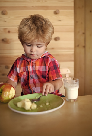Kid or blonde happy boy eating apple.の写真素材