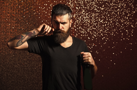 Bearded man twirl mustache with bottle on bokeh backgroundの写真素材