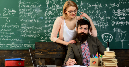 Teacher or tutor helps preschool child, Business tutor typing on laptop at workplace in classroom,...