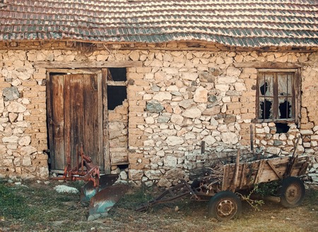Abandoned cart next to ruins. Old cart near stone wall. District with old buildings, old building made of stones collapsing. The uninhabited house almost destroyedの写真素材