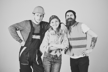 Repair brigade concept. Teamwork, full service, brigade. Company of cheerful workers, builder, repairer, plasterer. Man and woman with smiling faces in helmet and boilersuit, grey backgroundの写真素材