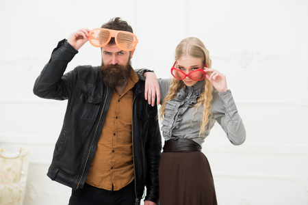 Stylish couple in huge orange glasses posing in studio. Man with nice beard and mustache hugging blond attractive girl. Fashion shooting. crazy fun coupleの写真素材