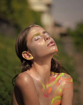 Young woman with colorful paint and closed eyesの写真素材