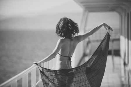 Woman in bikini travelling on cruise ship on sunny day. Vacation concept. Sexy lady walk on deck of cruise liner with sea on background. Nude young attractive girl on summer vacation, rear view.の写真素材