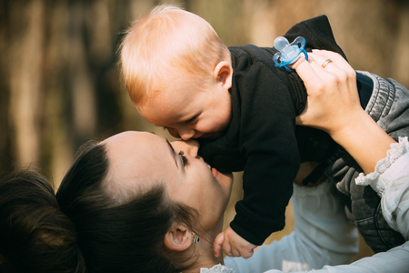 Happy family enjoy sunny day. Mother kiss little son with love. Woman play with child. Mom and baby boy outdoor. Mothers day concept. Love care and trust.の写真素材