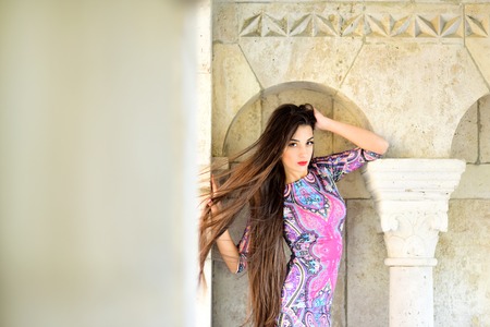 Sexy girl in long dress with brunette hair. sexy woman pose at stony column, copy spaceの写真素材