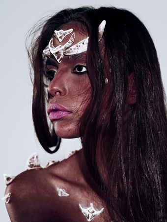 Portrait of woman with artistic make-up, Halloween concept. Face with thorns on red skin. Dark evil force. Complex work of professional makeup artist-stylist.の写真素材