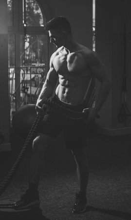 Sportsman, athlete with muscles does exercise with ropes. Sport and gym concept. Man with nude torso in gym enjoy his sporty lifestyle. Man with torso, muscular macho does functional training.の写真素材