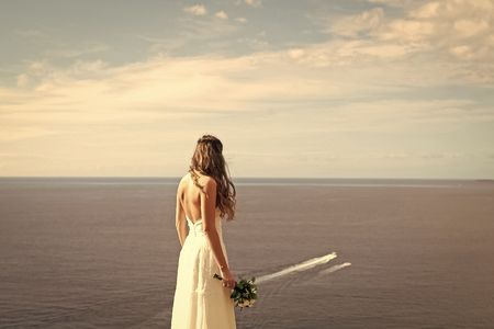 Sexy woman. Pretty bride in white dress with wedding bouquetの写真素材