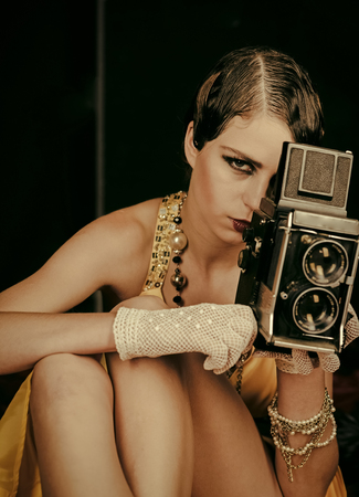 Face girl for magazine cover. Girl face portrait in your advertisnent. media and new technology, journalism. beauty, retro look, pinup fashion. Pin up pretty fashion model photographer. Woman with retro hair, makeup and old camera. Girl with vintage photo camera.の写真素材