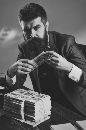 Man sitting at the table with piles of money, counting profit.の写真素材