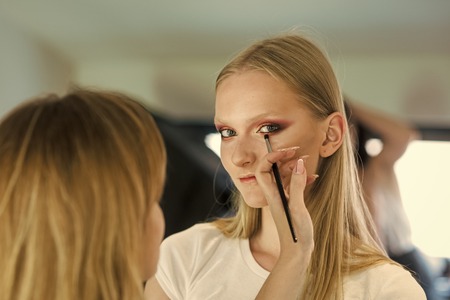 Woman getting glamour eye makeup, look. Makeup artist apply eye shadow with brush, visage. Woman with young face skin in beauty salon. Face girl for magazine cover. Girl face portrait in your advertisnent.の写真素材