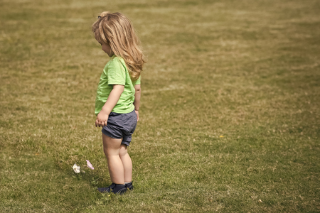 Child Childhood Children Happiness Concept. Small boy with long blond hair looking at white flowerの写真素材